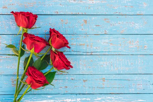 Romantic bunch of red rose flowers on blue wooden background with copy space