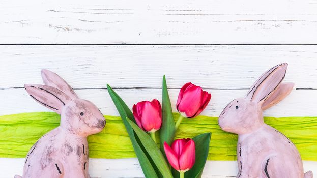 Happy easter background with rabbits and bunch of tulip flowers on white wood