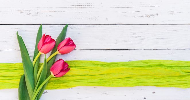 Red tulips spring flowers arrangement on white wooden background with copy space