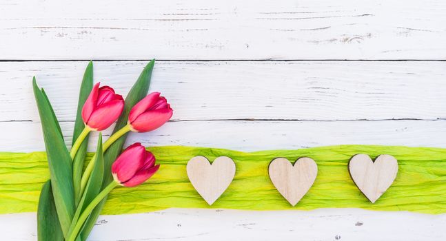 Romantic love background with red flowers and hearts frame on white wood