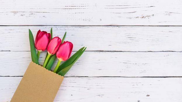 Red tulips bunch on white wooden background with copy space