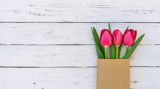 Arrangement of red tulip flowers on white wood background with copy space