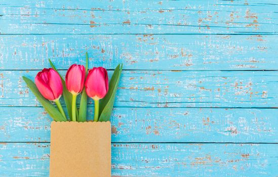 Bunch of red tulips on blue wooden background with copy space