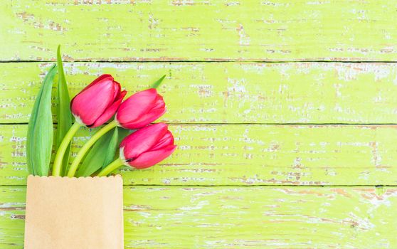 Red tulip spring flowers on green wooden background with copy space