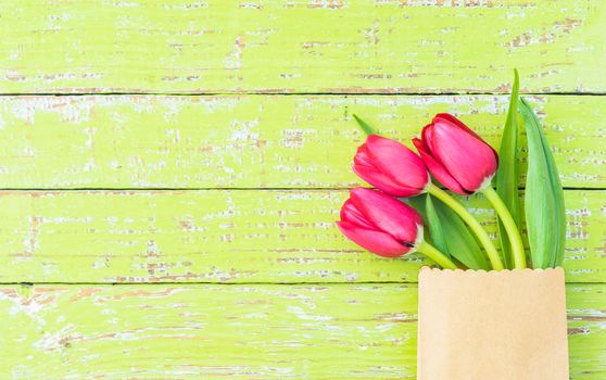 Bunch of red tulips on green wooden background with copy space 
