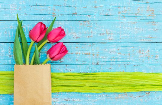 Red tulip flowers arrangement on blue wooden background with copy space
