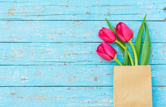 Fresh red tulips arrangement on blue wooden background with copy space