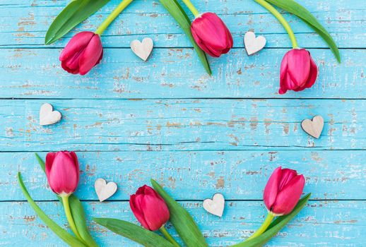 Romantic love background for Valentine day with hearts and red tulip flowers on blue wood