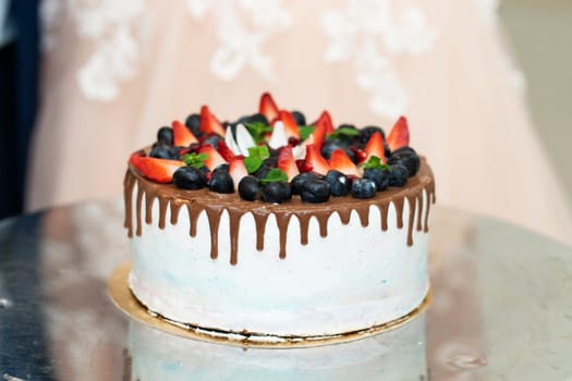 Round festive cake with fresh berries and chocolate.
