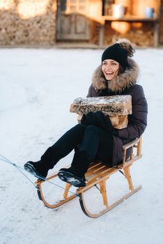 girl sitting in a sled, smiling and holding a wooden log in her hands