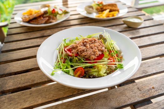 Restaurant serving food. Tuna salad in a plate on a table in a summer cafe.