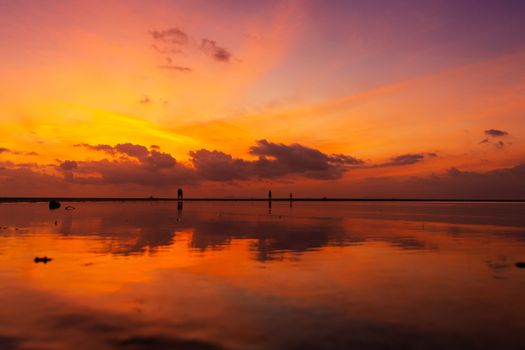 Burning bright sky during sunset on a tropical beach. Sunset during the exodus, the strength of people walking on water.