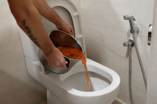The girl pours a pot of soup into the toilet. Spoiled food.