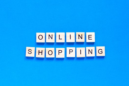 Online Shopping inscription in wooden letters on a blue background. The concept of business of online purchases of delivery .