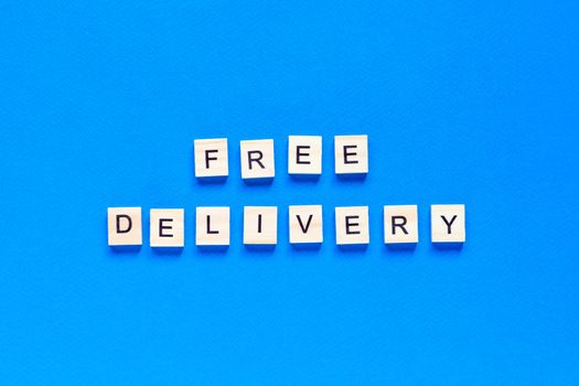 free shipping lettering in wooden letters on a blue background, top view. Service concept, delivery, contactless delivery, promotion, free of charge.