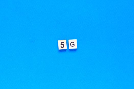 5 G. Five G's, written in wooden letters on a blue background. Flat layout. Wireless network. New technology. top view.
