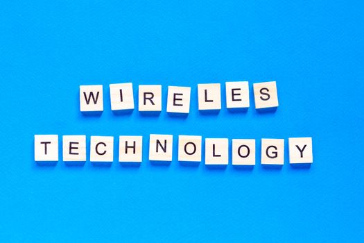 wireless technology lettering in wooden letters. The words wireless technology, spelt with wooden letter tiles over a white background.