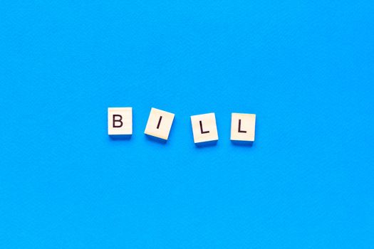 bill in wooden letters on a blue background, flat layout, top view, classic blue color