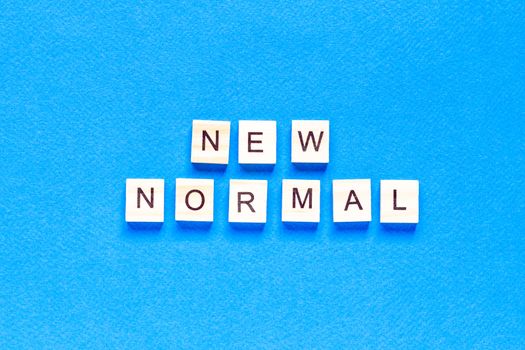 NEW NORMAL word on wooden alphabet cube. New normal concept. flat layout. top view