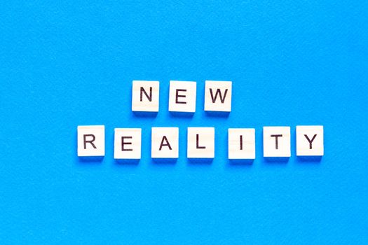 NEW REALITY. the words new reality are written in wooden letters on a blue background. top view. flat layout.
