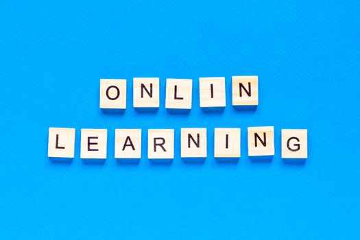 online learning concepts written in wooden letters on a blue background. a top view of a flat layout, online school. a new form of learning