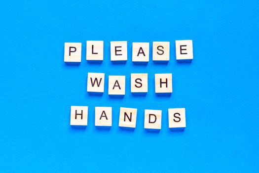 please wash your hands, written in wooden letters on a blue background, warning, request, flat layout, top view,