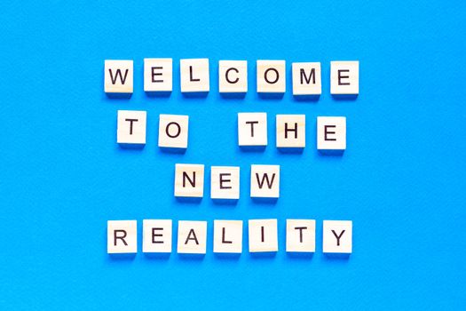 the inscription welcome to the new reality in wooden letters on a blue background. the view from the top. Modern technologies, a new device of the world