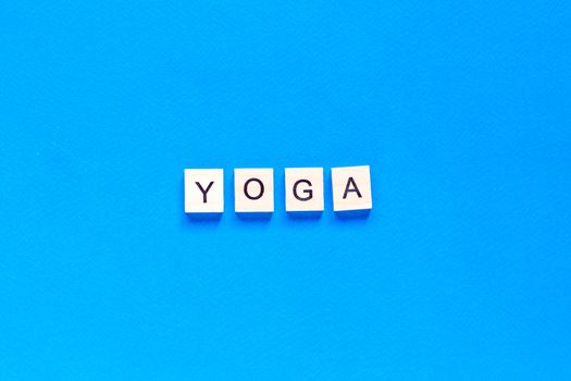 The word YOGA written in wooden letterpress type on a blue background. top view. flat layout.