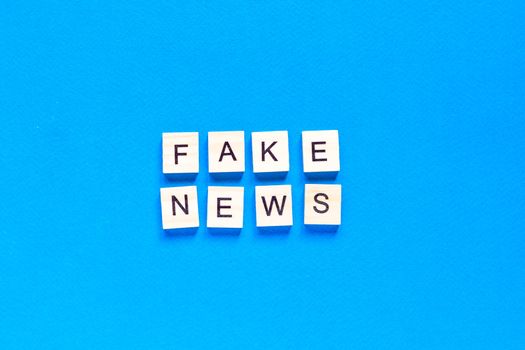 Fake news word alphabet letters on blue background. flat layout. top view.
