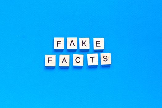 Fake facts word alphabet letters on blue background. flat layout. top view.