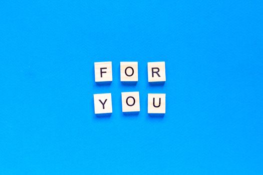 FOR YOU written in wooden letters on a blue background. top view, flat layout, I'll do anything for you