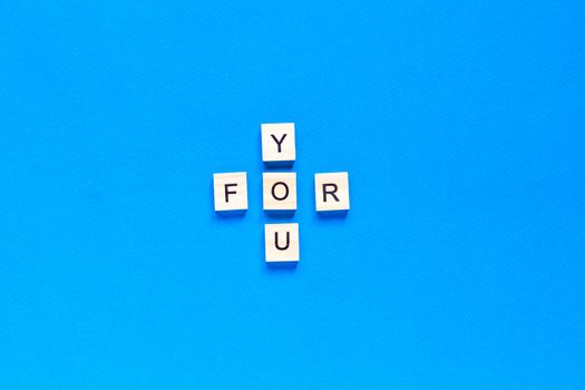 FOR YOU written in wooden letters on a blue background. top view, flat layout.