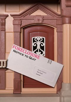 Envelope being served at toy dollhouse containing a foreclosure notice due to failure to pay rent on the property