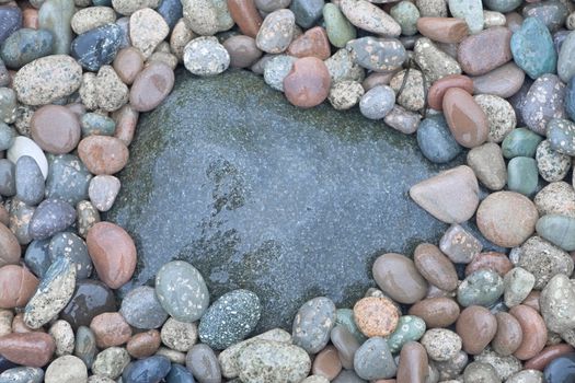 2 - One large, wet and dark stone surrounded by many lighter pebbles, great background texture with copy space.