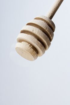 Traditional wooden honey dipper on a gray background