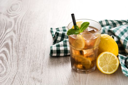 Iced tea drink with lemon in glass on white wooden table