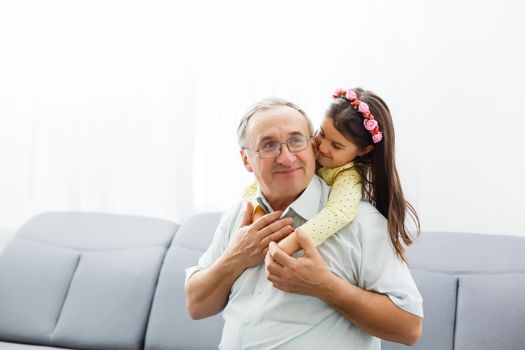 Funny lifestyle portrait of grandchild embracing grandfather