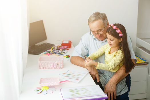 Caring grandfather doing home assignment together with granddaughter