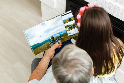 Granddaughter and grandfather watching photos together in a photo album at home