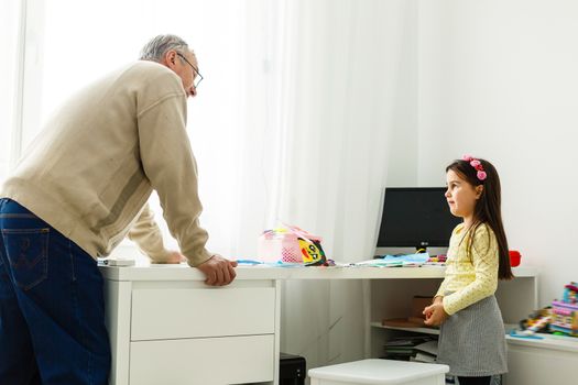 Grandfather talking and smiling with his granddaughter at table