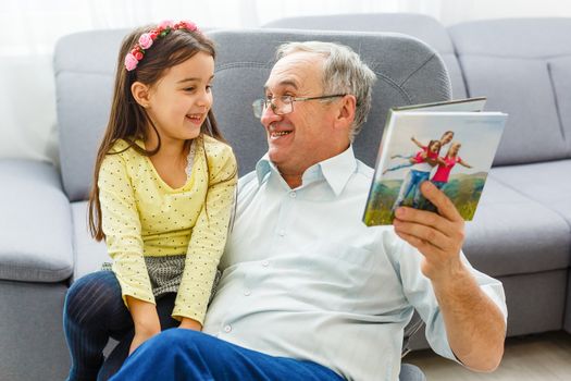 Granddaughter and grandfather watching photos together in a photo album at home