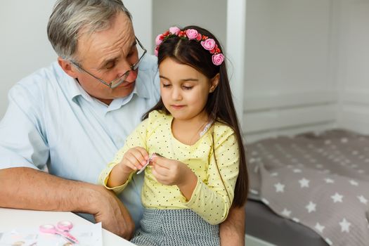 Caring grandfather doing home assignment together with granddaughter