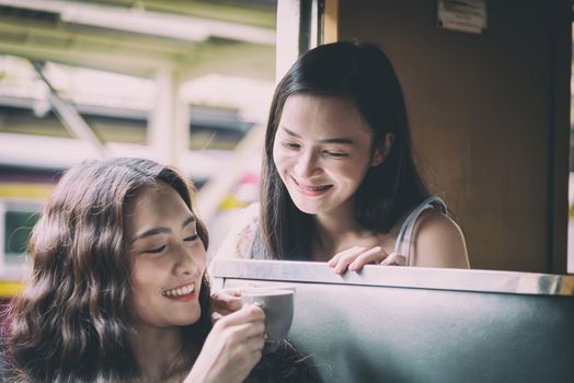 Asian women traveler have drinking a cup of coffee together with hapiness in the train at Hua Lamphong station at Bangkok, Thailand.