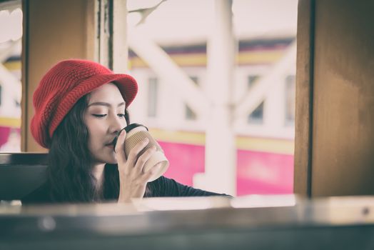 Asian woman traveler has drinking a cup of coffee with traveling by train at Hua Lamphong station at Bangkok, Thailand.