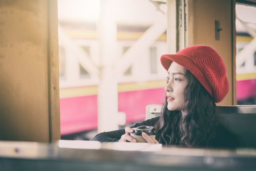 Asian woman traveler has drinking a cup of coffee with traveling by train at Hua Lamphong station at Bangkok, Thailand.