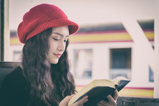 Asian woman traveler has reading a book in the train with happiness at Hua Lamphong station at Bangkok, Thailand.