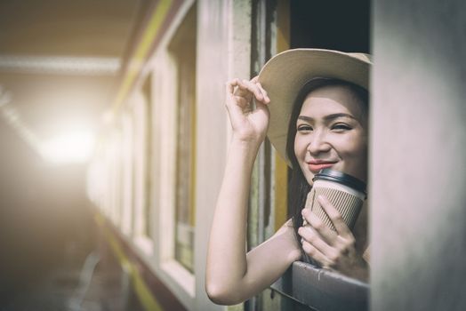 Asian woman traveler has drinking coffee in the train with happiness at Hua Lamphong station at Bangkok, Thailand.