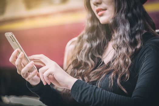 Asian woman traveler has playing with phone and waiting the train at Hua Lamphong station at Bangkok, Thailand.