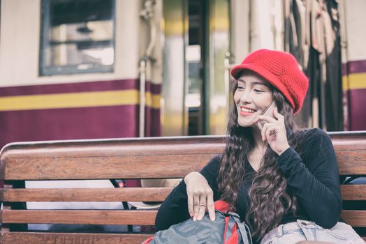 Asian woman traveler has talking with phone and waiting the train at Hua Lamphong station at Bangkok, Thailand.