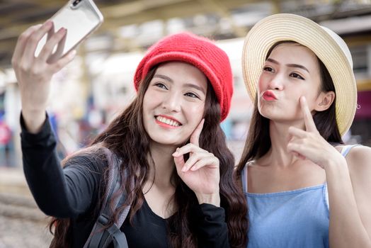 Asian women traveler have playing a mobile phone and talking for waiting the train with happiness at Hua Lamphong station at Bangkok, Thailand.